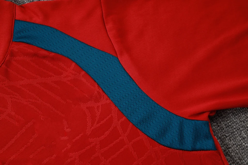 Close-up of contrasting teal textured side panel on red soccer training top
