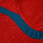 Close-up of contrasting teal textured side panel on red soccer training top